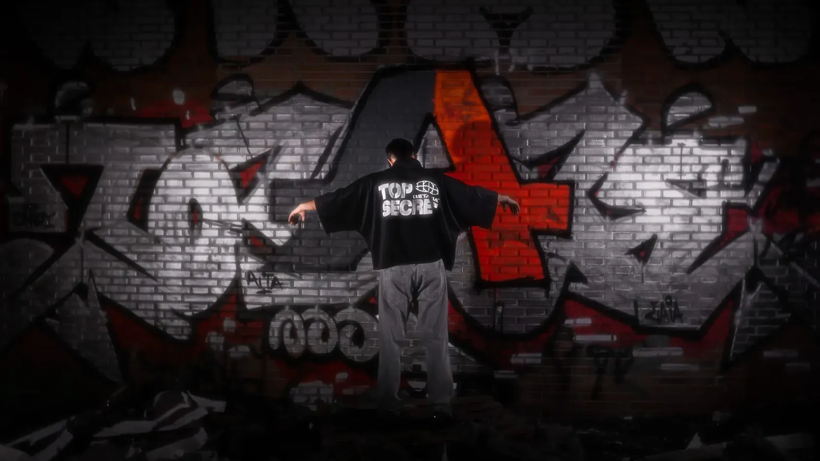 Chico con una sudadera de Getaria ante un muro de grafiti con la A de la marca