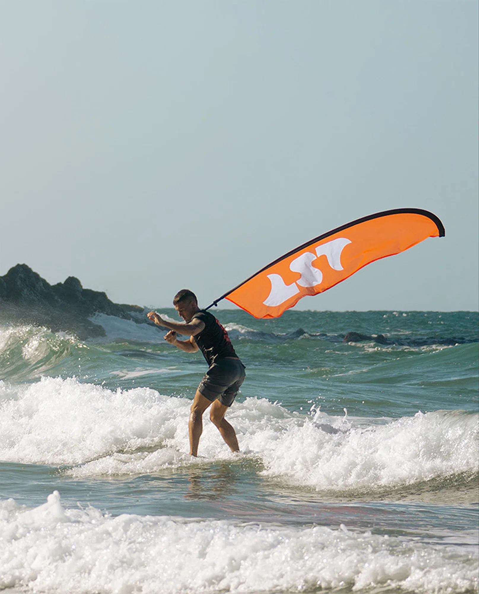Surfista con una vela naranja con el isotipo