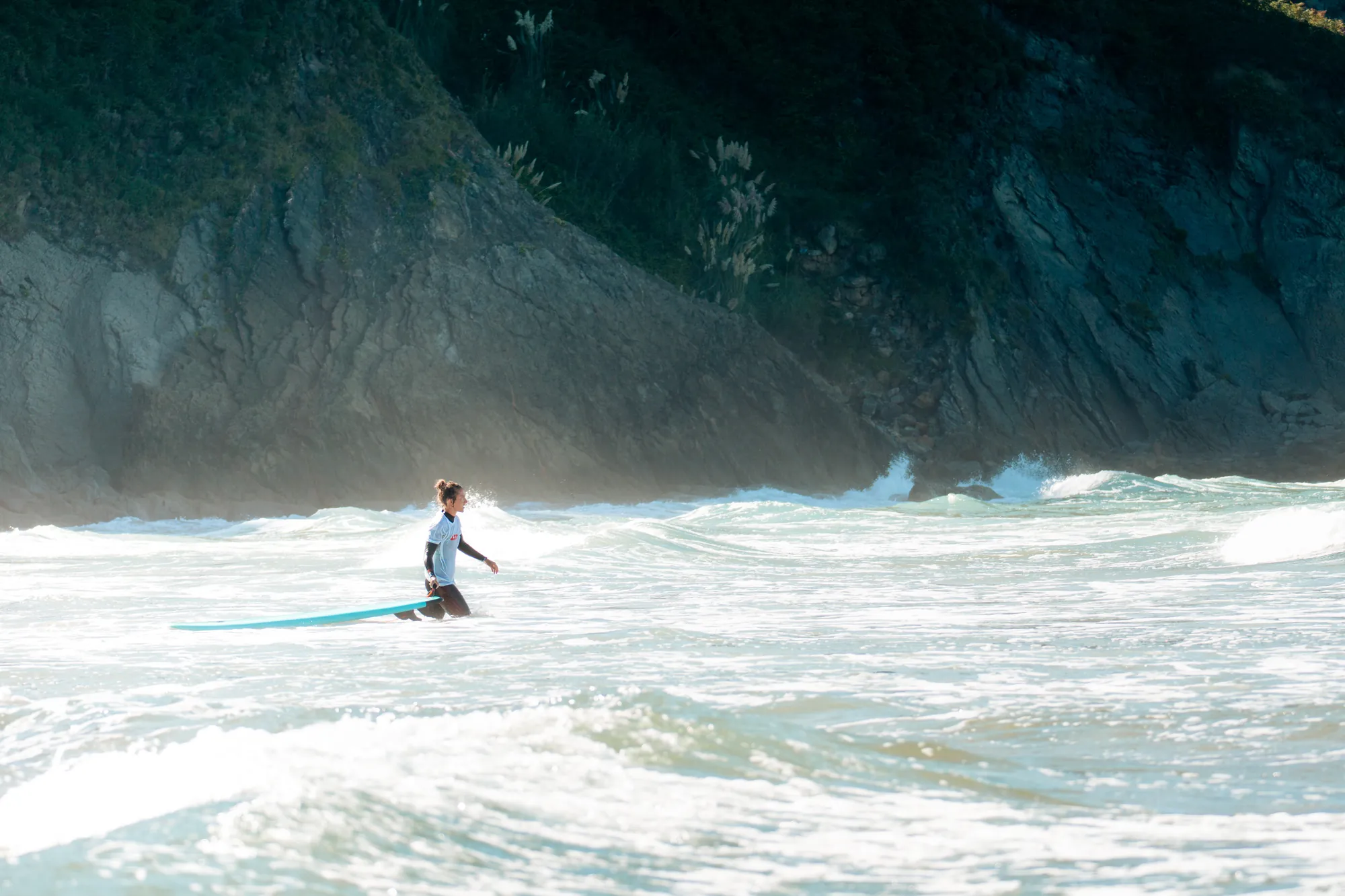 Surfista frente a un acantilado entre la espuma