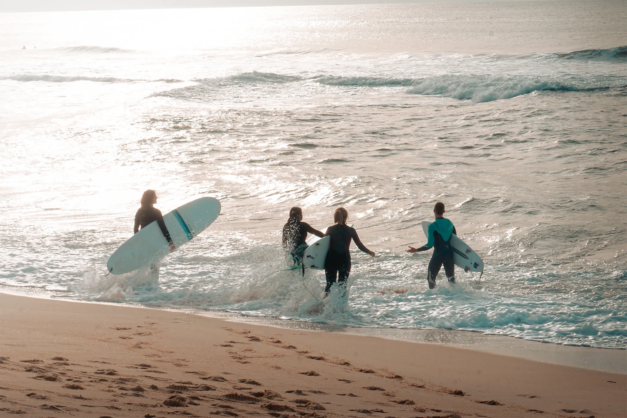 Surfistas entrando al mar en una playa