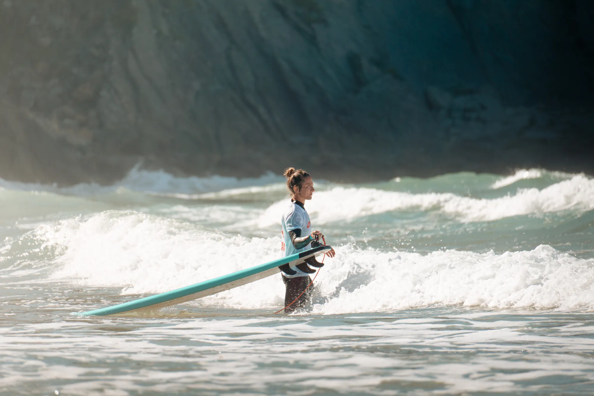Surfista con la tabla bajo el brazo entre la espuma