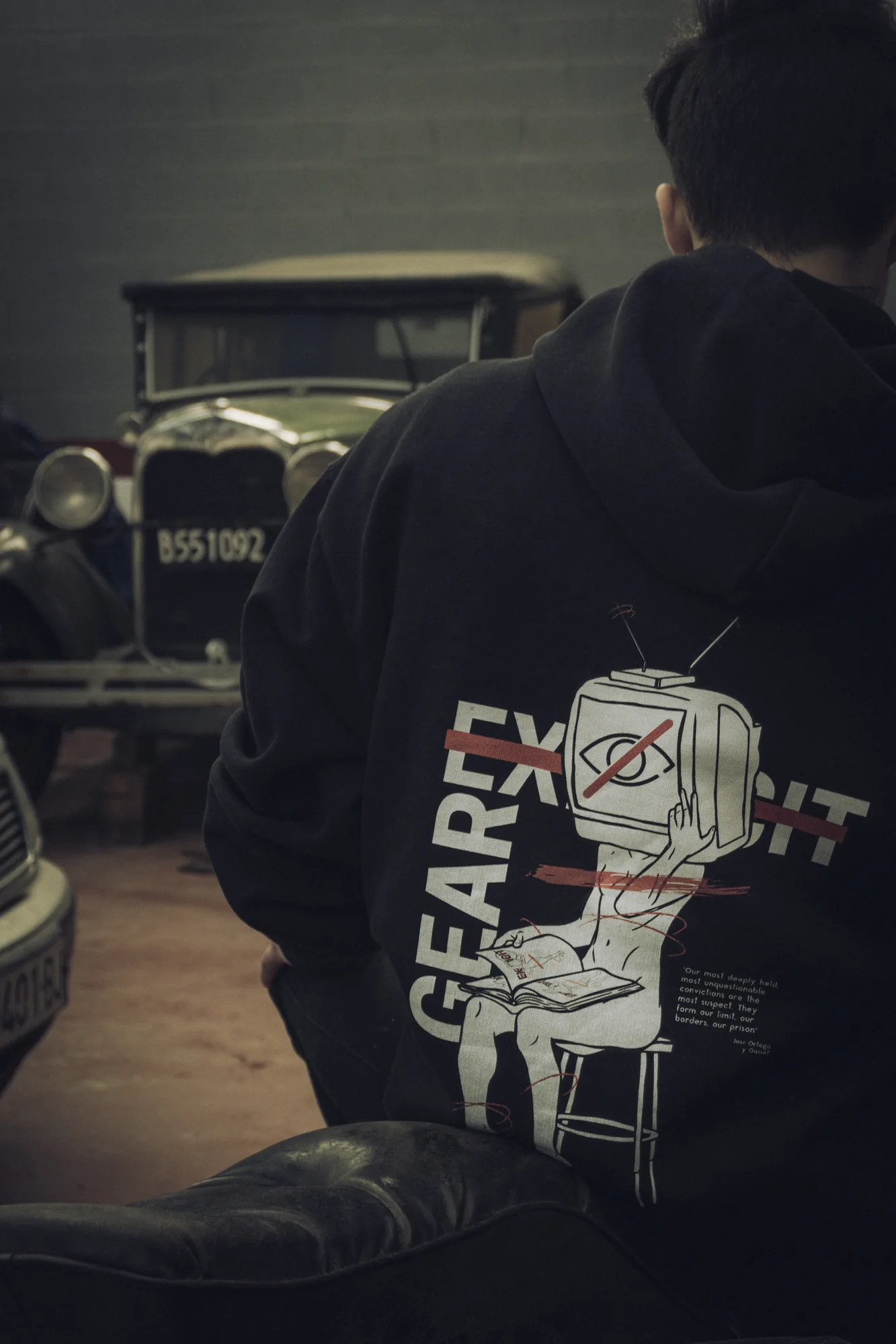 La gráfica del televisor en una sudadera negra, ante un coche clásico