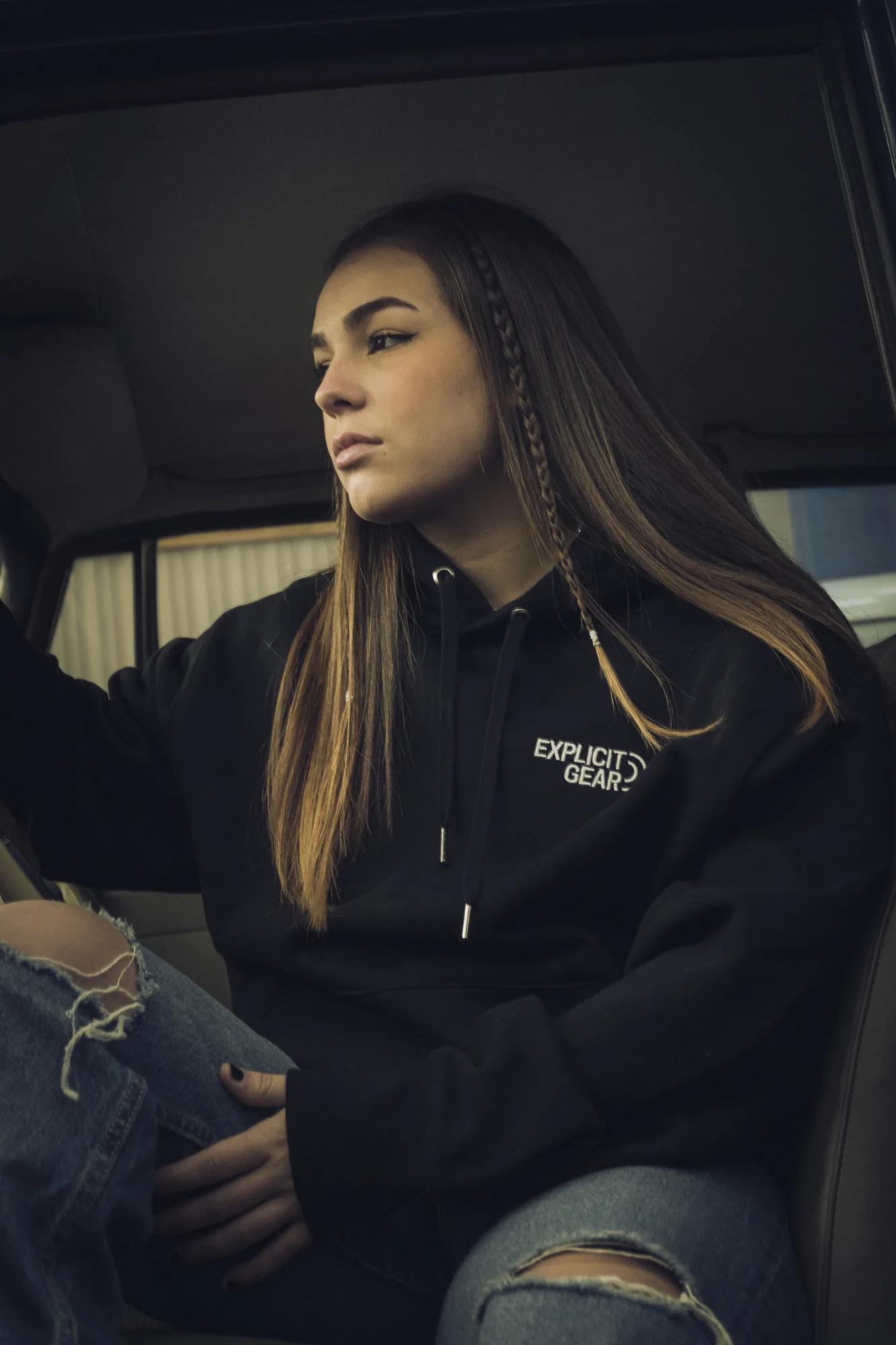 Chica con la sudadera negra de Explicit Gear sentada en un coche