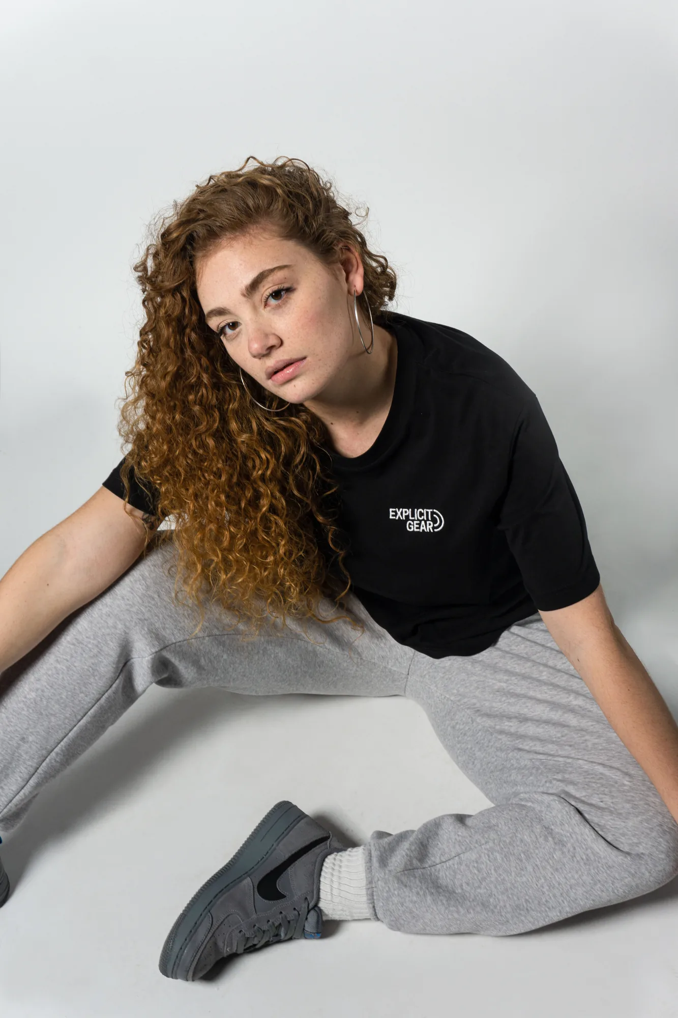 Chica sentada en el suelo con la camiseta negra de Explicit Gear
