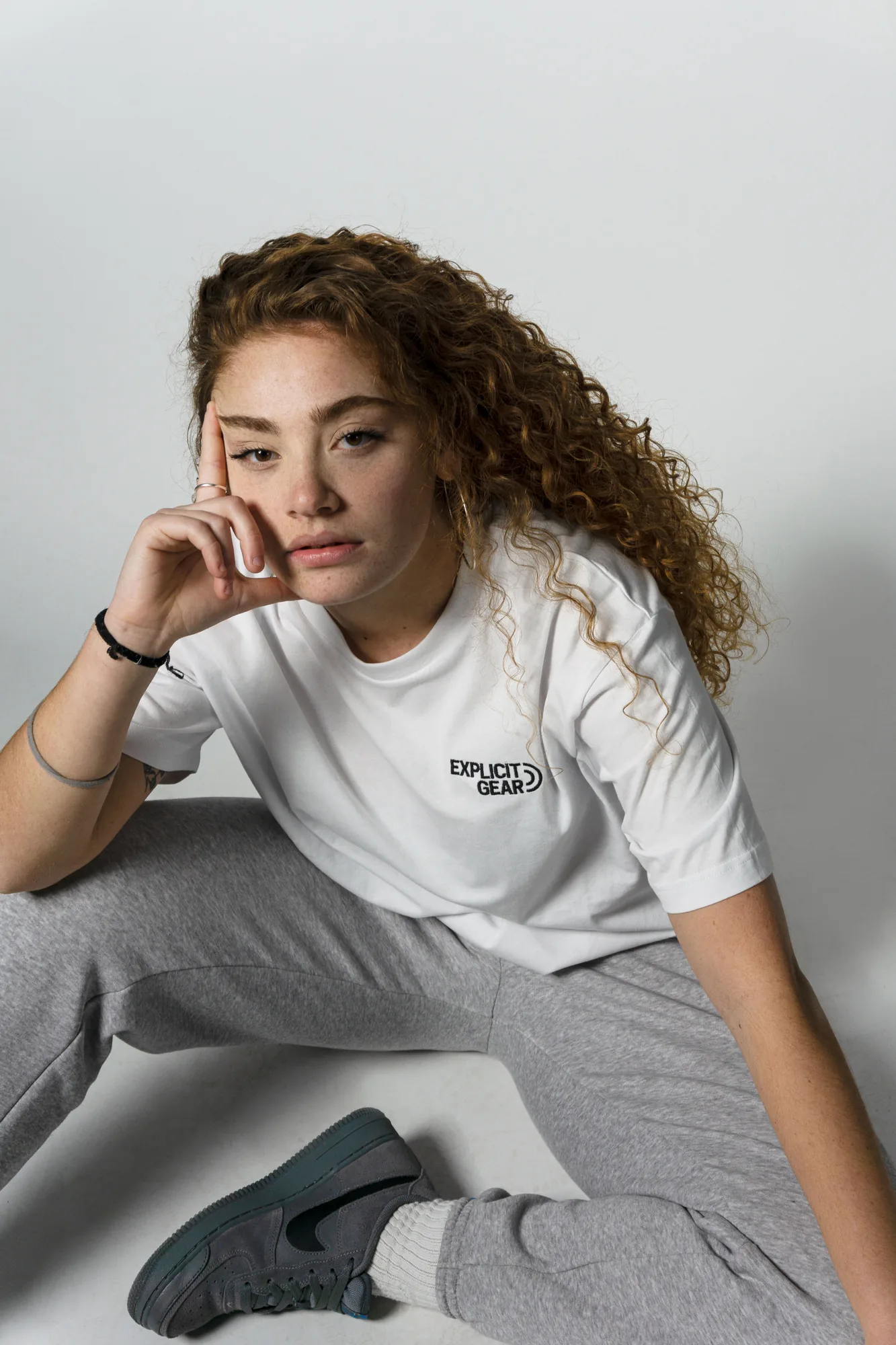 Chica sentada en el suelo con la camiseta blanca de Explicit Gear