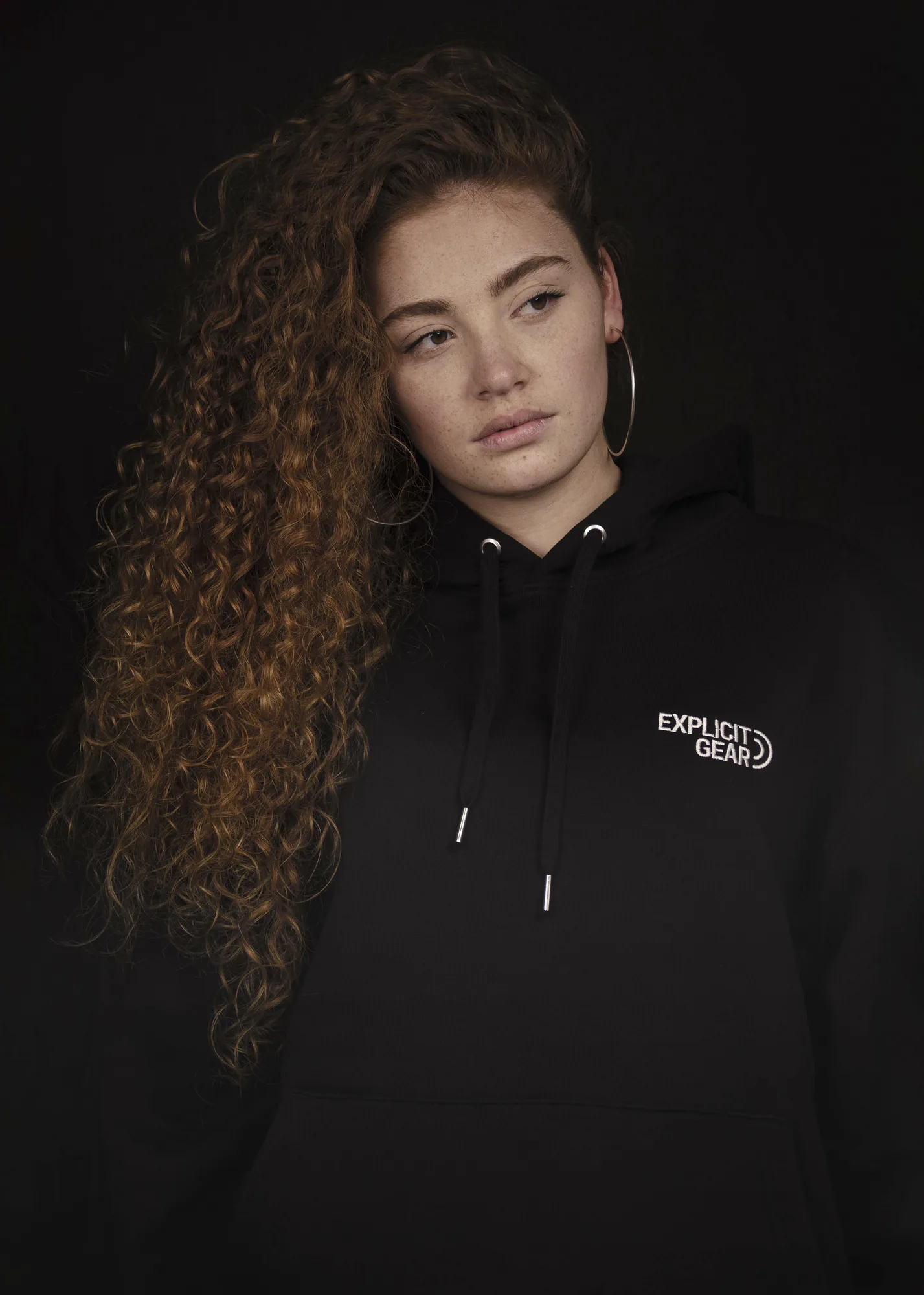 Chica de pelo rizado con la sudadera negra de Explicit Gear