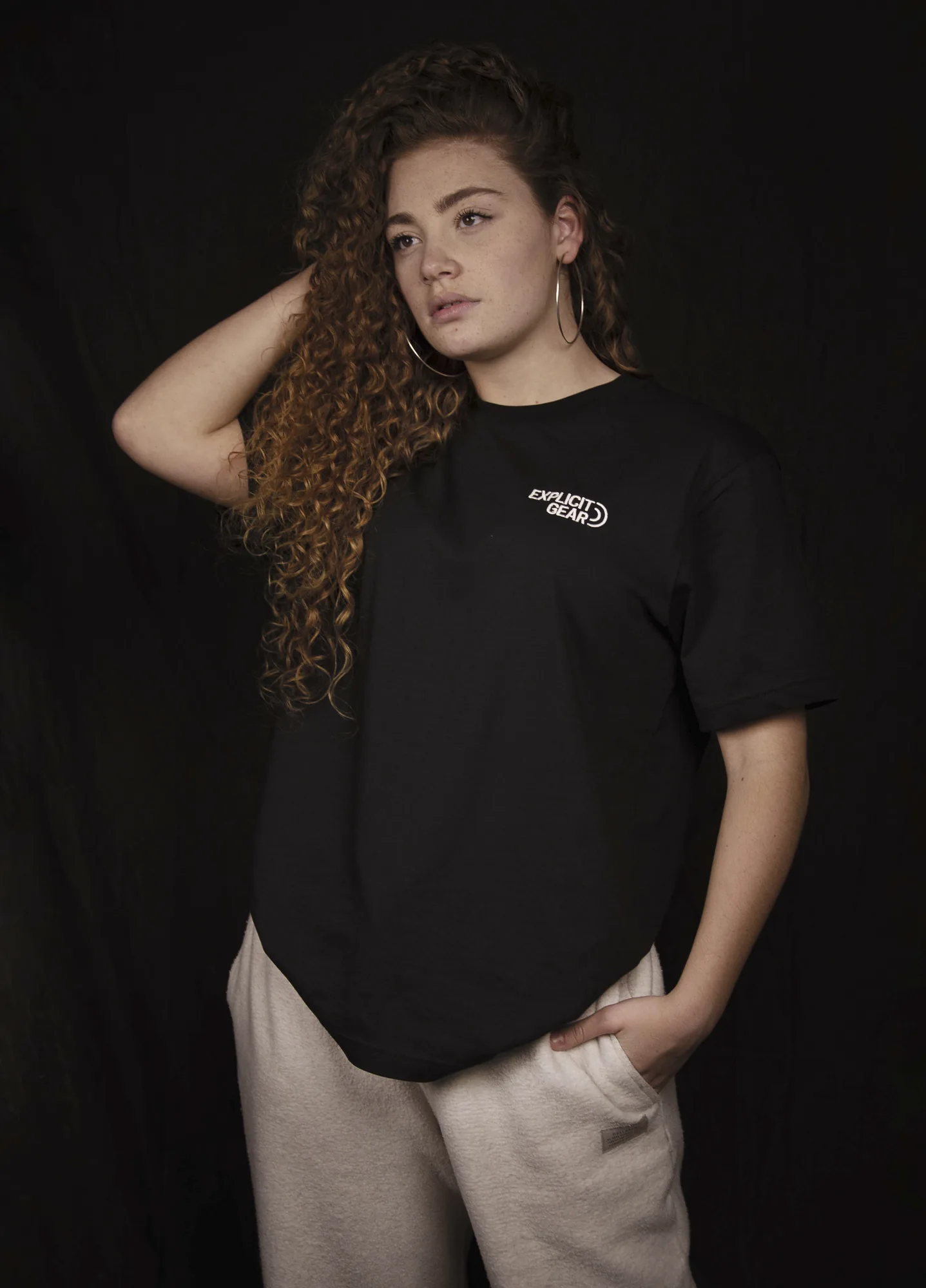 Chica con la camiseta negra de Explicit Gear y la mano en el pelo