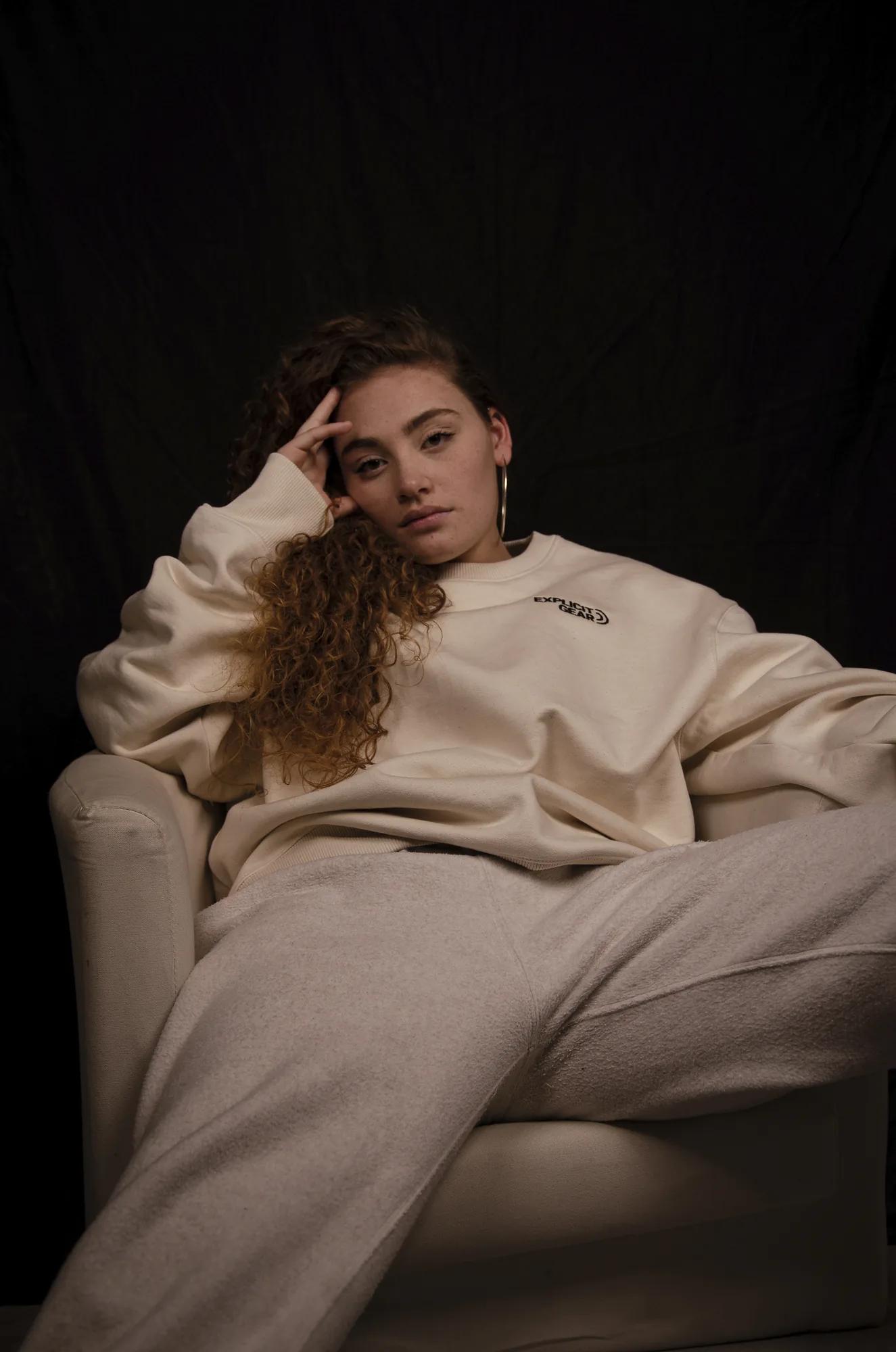 Chica recostada en un sillón con el conjunto crema