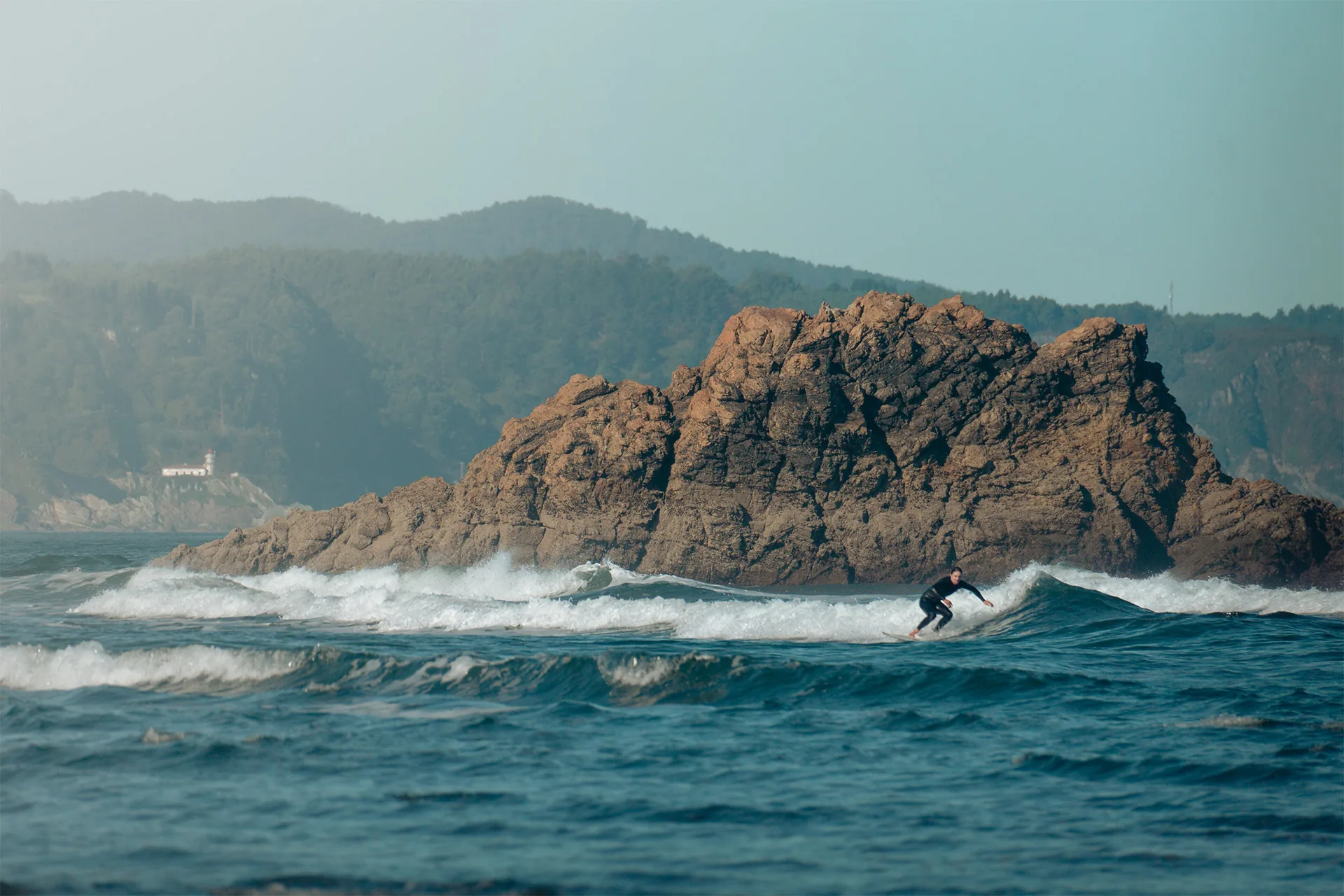 Surfista frente a un islote de roca