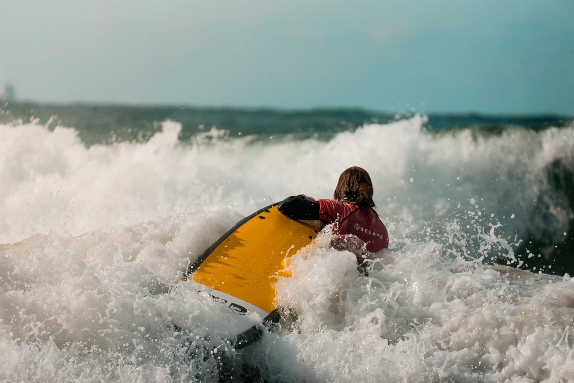 Surfista con tabla amarilla entre la espuma