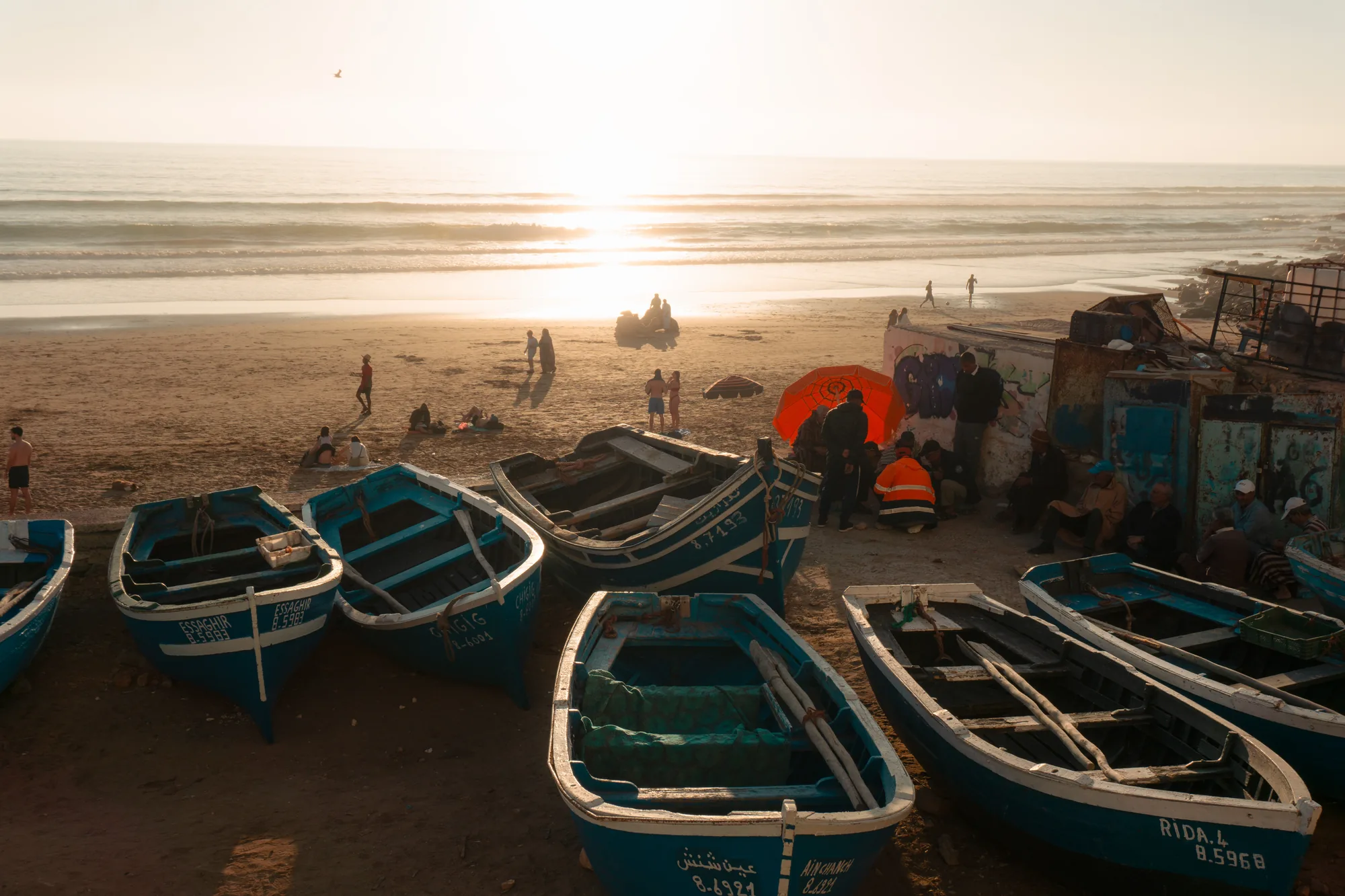 Barcas de pesca azules varadas en la arena al atardecer